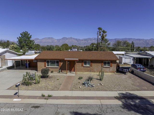 view of front of property featuring a mountain view, brick siding, a carport, and concrete driveway