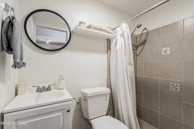 bathroom with vanity, toilet, and tiled shower