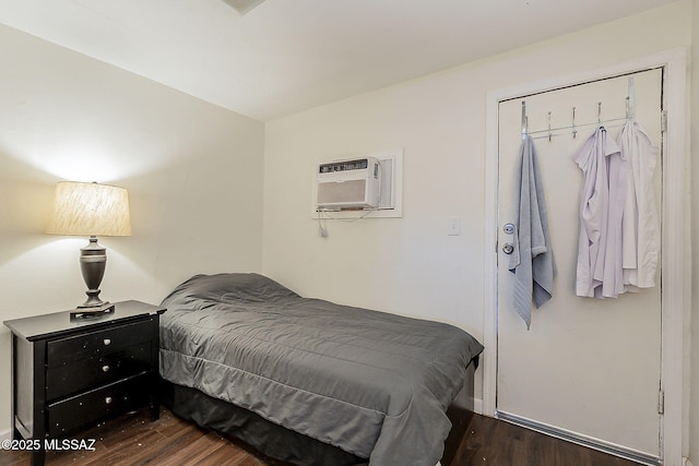 bedroom featuring a wall mounted air conditioner, baseboards, and dark wood finished floors