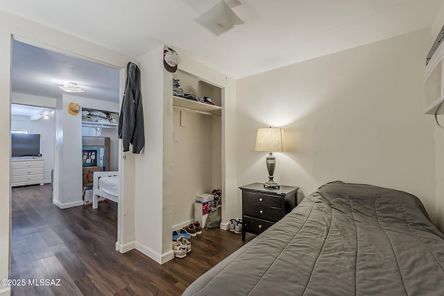 bedroom with baseboards, a closet, and dark wood-type flooring