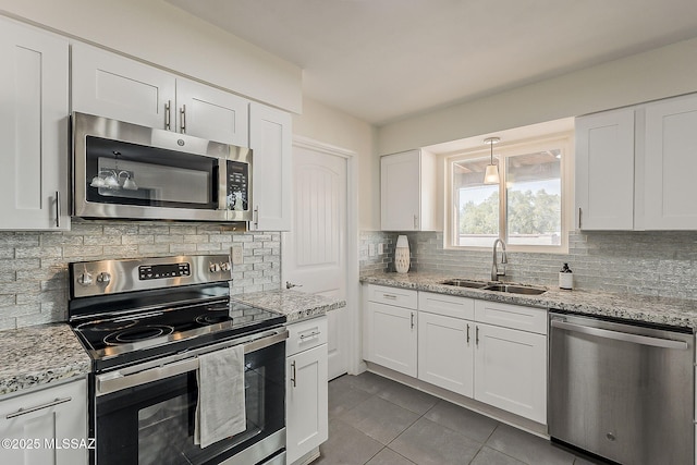 kitchen featuring white cabinetry, decorative backsplash, a sink, appliances with stainless steel finishes, and tile patterned flooring