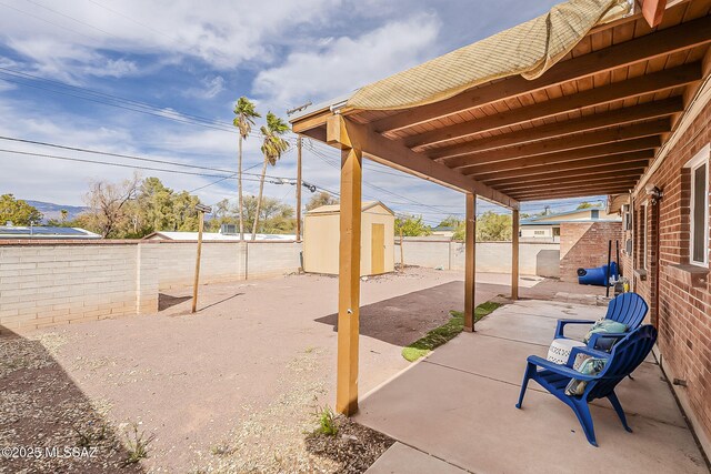 view of patio / terrace with a storage unit, a fenced backyard, and an outbuilding