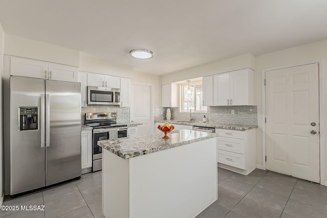 kitchen featuring decorative backsplash, light tile patterned floors, appliances with stainless steel finishes, a sink, and white cabinetry