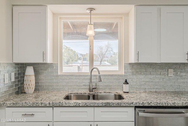 kitchen featuring light stone countertops, a sink, backsplash, stainless steel dishwasher, and white cabinets