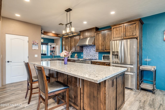kitchen featuring extractor fan, light wood-type flooring, appliances with stainless steel finishes, and a kitchen island