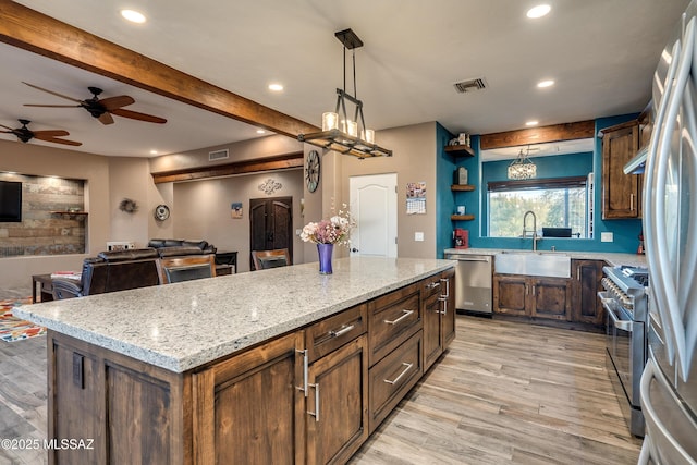 kitchen with light wood finished floors, a sink, ceiling fan, stainless steel appliances, and beamed ceiling