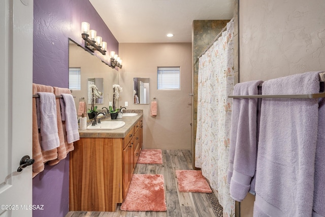 full bath featuring double vanity, wood finished floors, a shower with shower curtain, and a sink
