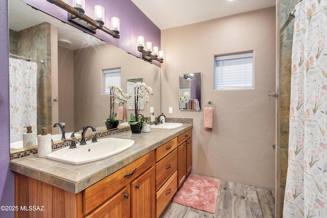 bathroom with double vanity, wood finished floors, a shower with curtain, and a sink