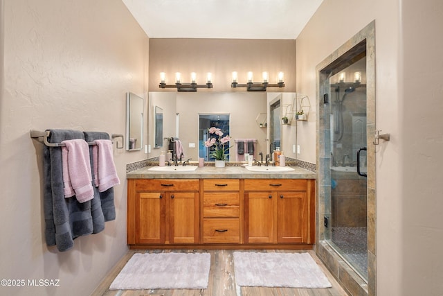 full bath featuring a sink, a stall shower, and double vanity