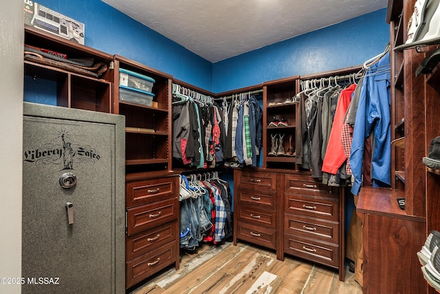 walk in closet with light wood-style floors