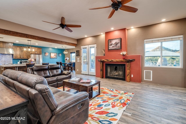 living area featuring recessed lighting, ceiling fan, a fireplace, and light wood finished floors