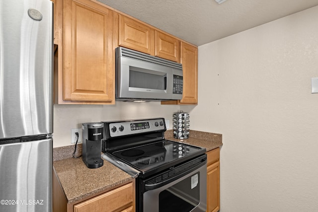 kitchen with a textured ceiling, dark countertops, and stainless steel appliances