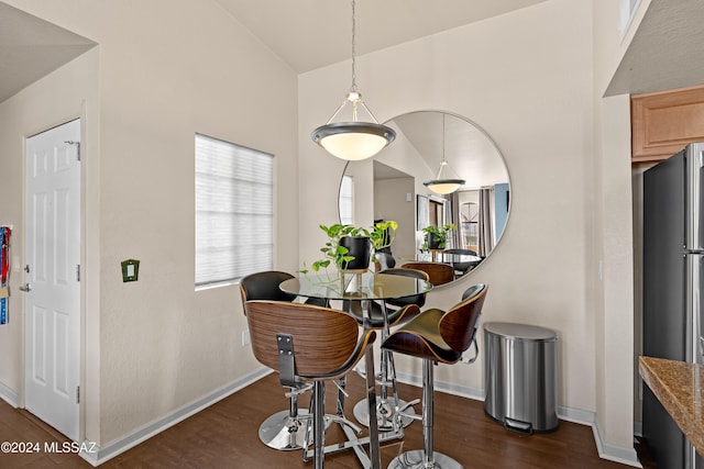 dining space featuring dark wood-style floors, lofted ceiling, and baseboards