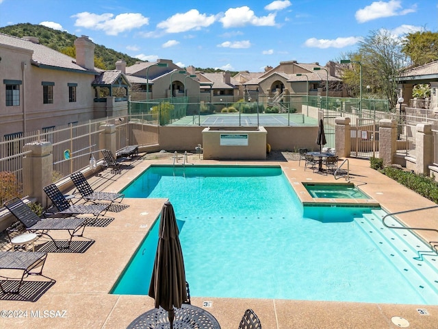 pool with a patio area, a residential view, a hot tub, and fence