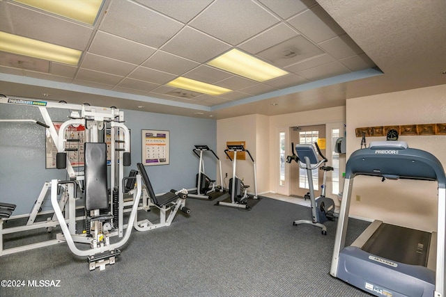 gym with a tray ceiling and a drop ceiling