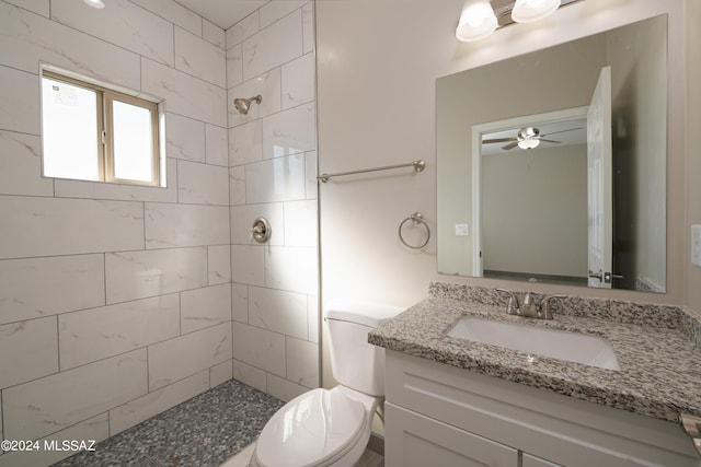 full bath featuring vanity, a ceiling fan, a tile shower, and toilet