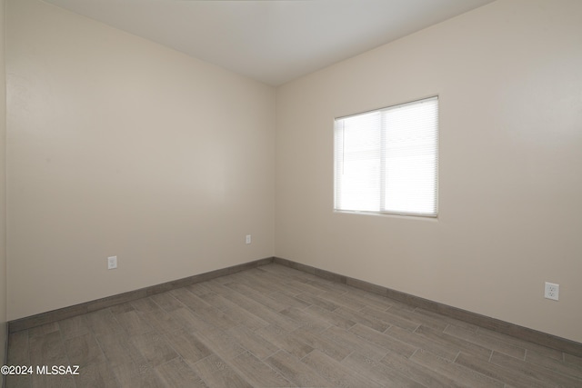spare room with baseboards and wood finished floors