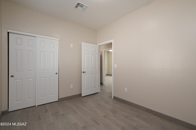 unfurnished bedroom featuring baseboards, a closet, wood finished floors, and visible vents