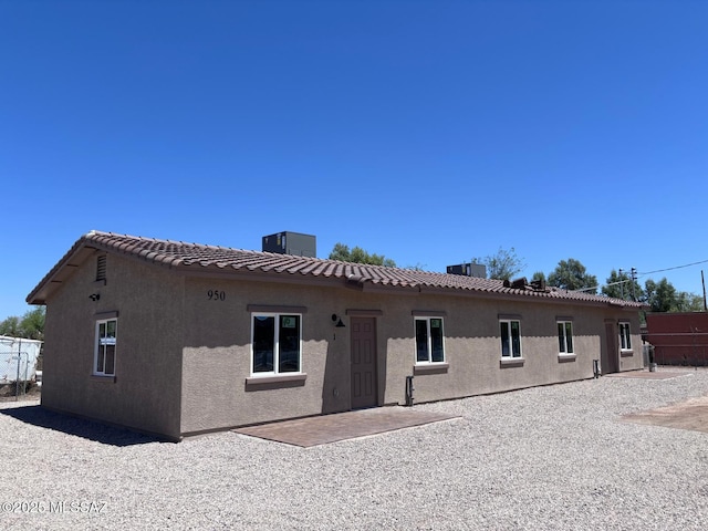 rear view of house with central AC, a tile roof, and stucco siding