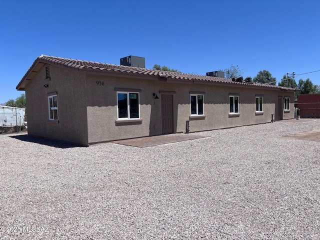 rear view of property with a tile roof and stucco siding
