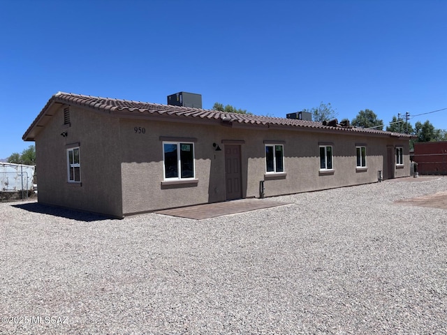 rear view of property featuring central air condition unit, stucco siding, and a tiled roof