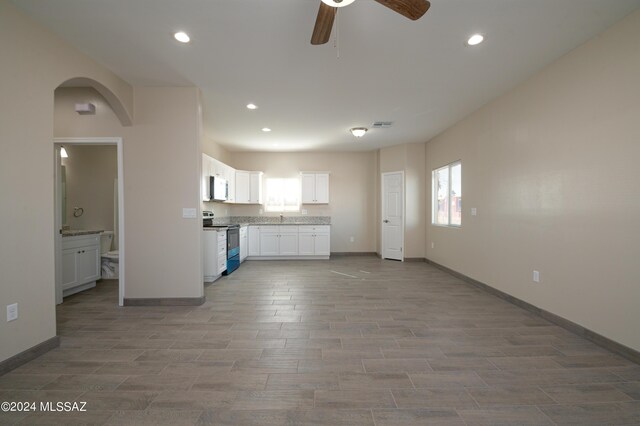 kitchen featuring baseboards, white microwave, white cabinets, a ceiling fan, and stainless steel electric range oven