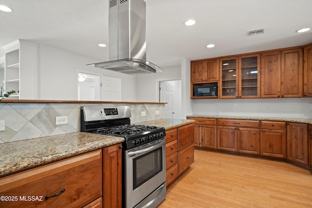 2350 E Juanita St, Tucson, AZ 85719 - kitchen featuring gas stove, island range hood, brown cabinetry, backsplash, and light wood-type flooring