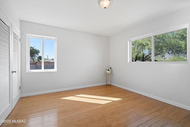 2350 E Juanita St, Tucson, AZ 85719 - unfurnished bedroom featuring multiple windows, light wood-type flooring, and baseboards