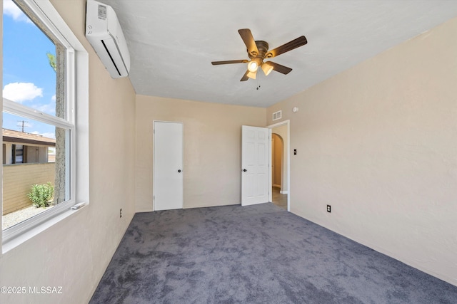 unfurnished bedroom with visible vents, a wall mounted air conditioner, a ceiling fan, and carpet floors