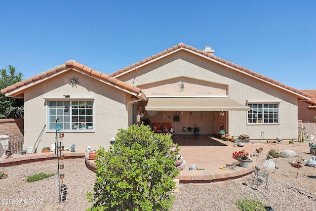 view of front facade featuring fence, stucco siding, a patio, and a garage