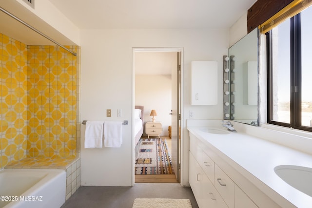 ensuite bathroom with double vanity, a bath, ensuite bathroom, and a sink