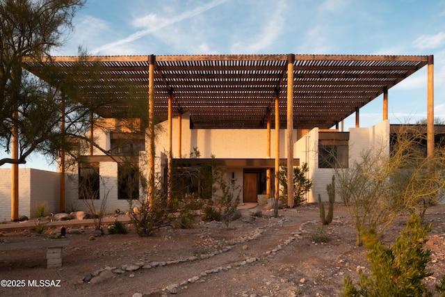 back of property with a pergola and stucco siding