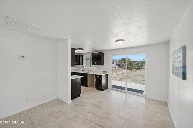 7575 E Apple Tree Dr, Tucson, AZ 85730 - kitchen featuring a sink, light countertops, baseboards, and light marble finish flooring