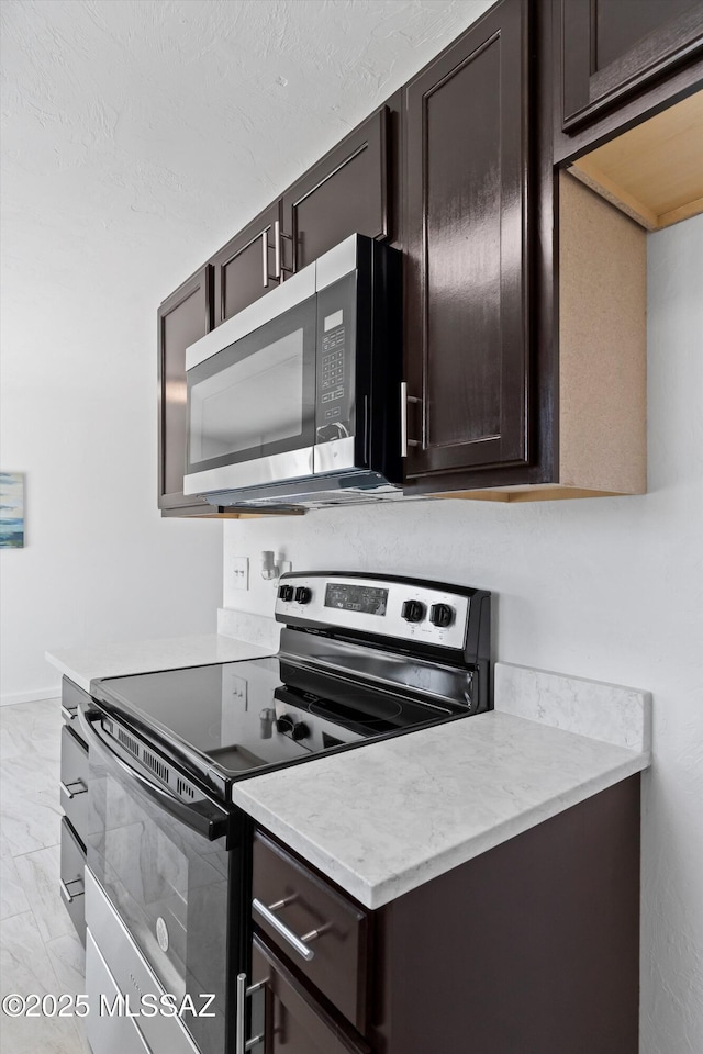 7575 E Apple Tree Dr, Tucson, AZ 85730 - kitchen with appliances with stainless steel finishes, dark brown cabinets, light countertops, and light marble finish floors