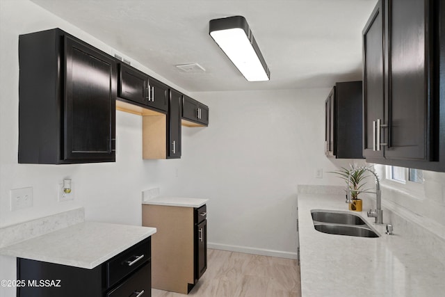 7575 E Apple Tree Dr, Tucson, AZ 85730 - kitchen with dark cabinetry, a sink, light countertops, and baseboards