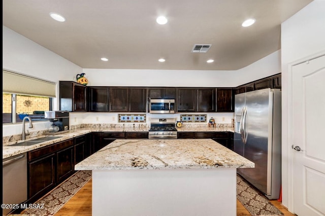 13978 N Big Wash Overlook Pl, Tucson, AZ 85739 - kitchen featuring appliances with stainless steel finishes, a sink, a center island, light stone counters, and light wood-style flooring