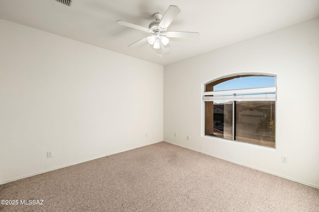 carpeted empty room featuring ceiling fan and baseboards