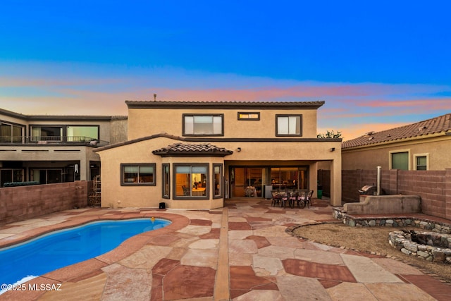 back of property with a patio area, a fenced backyard, a tiled roof, and a fenced in pool
