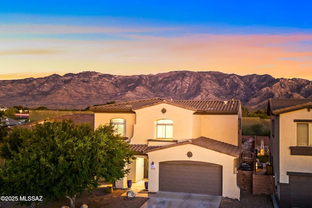 mediterranean / spanish-style house with concrete driveway, stucco siding, a tiled roof, and a mountain view