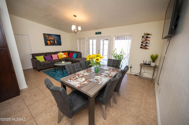 dining space with a chandelier, light tile patterned floors, french doors, and lofted ceiling