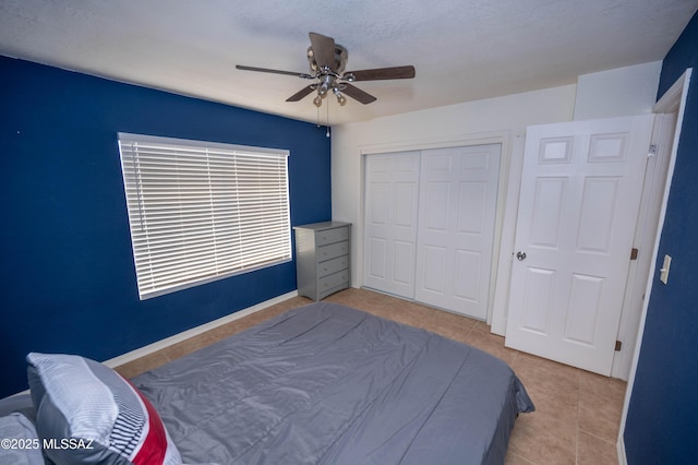 bedroom with tile patterned flooring, a ceiling fan, a closet, and baseboards
