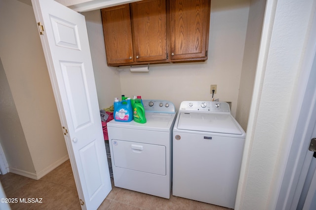 laundry room featuring baseboards, cabinet space, light tile patterned flooring, and washing machine and clothes dryer