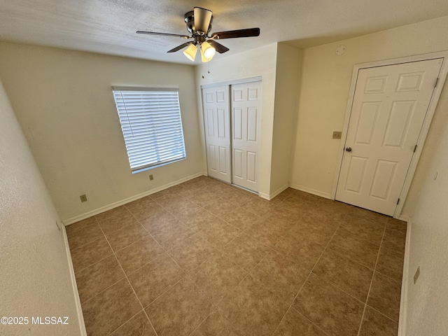 unfurnished bedroom featuring a textured ceiling, baseboards, a closet, and ceiling fan