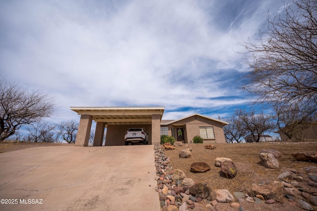 view of front of property featuring an attached carport, driveway, and stucco siding