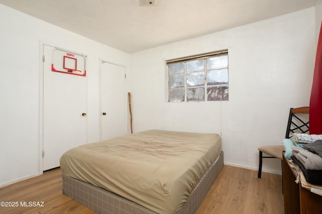 bedroom featuring light wood finished floors and baseboards