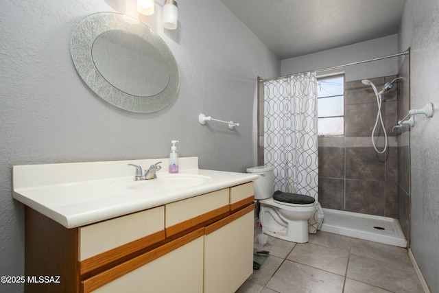 bathroom featuring baseboards, toilet, a tile shower, vanity, and tile patterned flooring