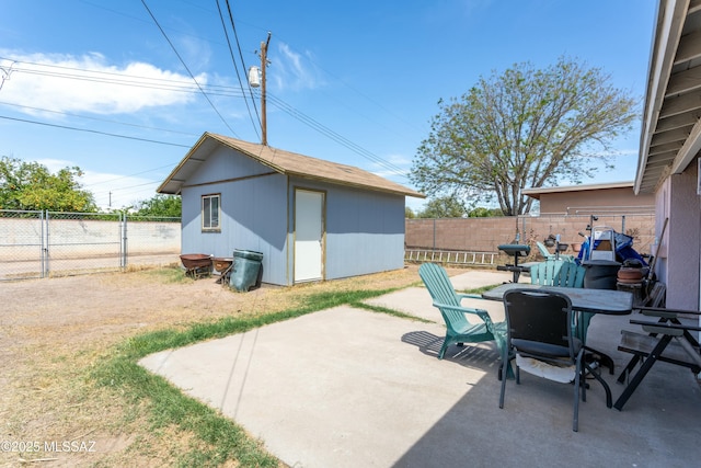 view of patio featuring outdoor dining space, a fenced backyard, a storage shed, and an outbuilding