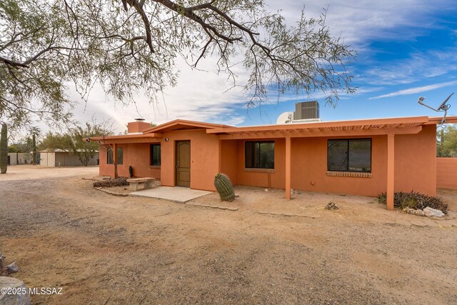 3053 W Lobo Rd, Tucson, AZ 85742 - back of house featuring cooling unit, fence, a chimney, and stucco siding
