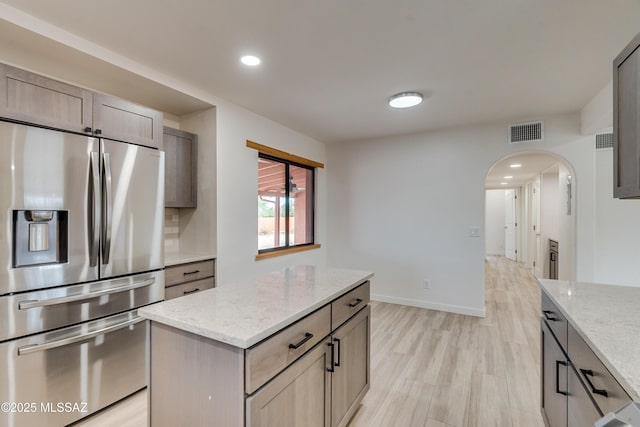 3053 W Lobo Rd, Tucson, AZ 85742 - kitchen featuring visible vents, light stone countertops, light wood-style flooring, stainless steel refrigerator with ice dispenser, and arched walkways