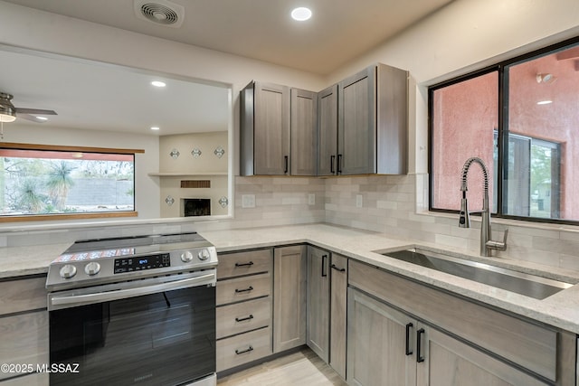 3053 W Lobo Rd, Tucson, AZ 85742 - kitchen featuring visible vents, backsplash, light stone countertops, stainless steel electric range oven, and a sink